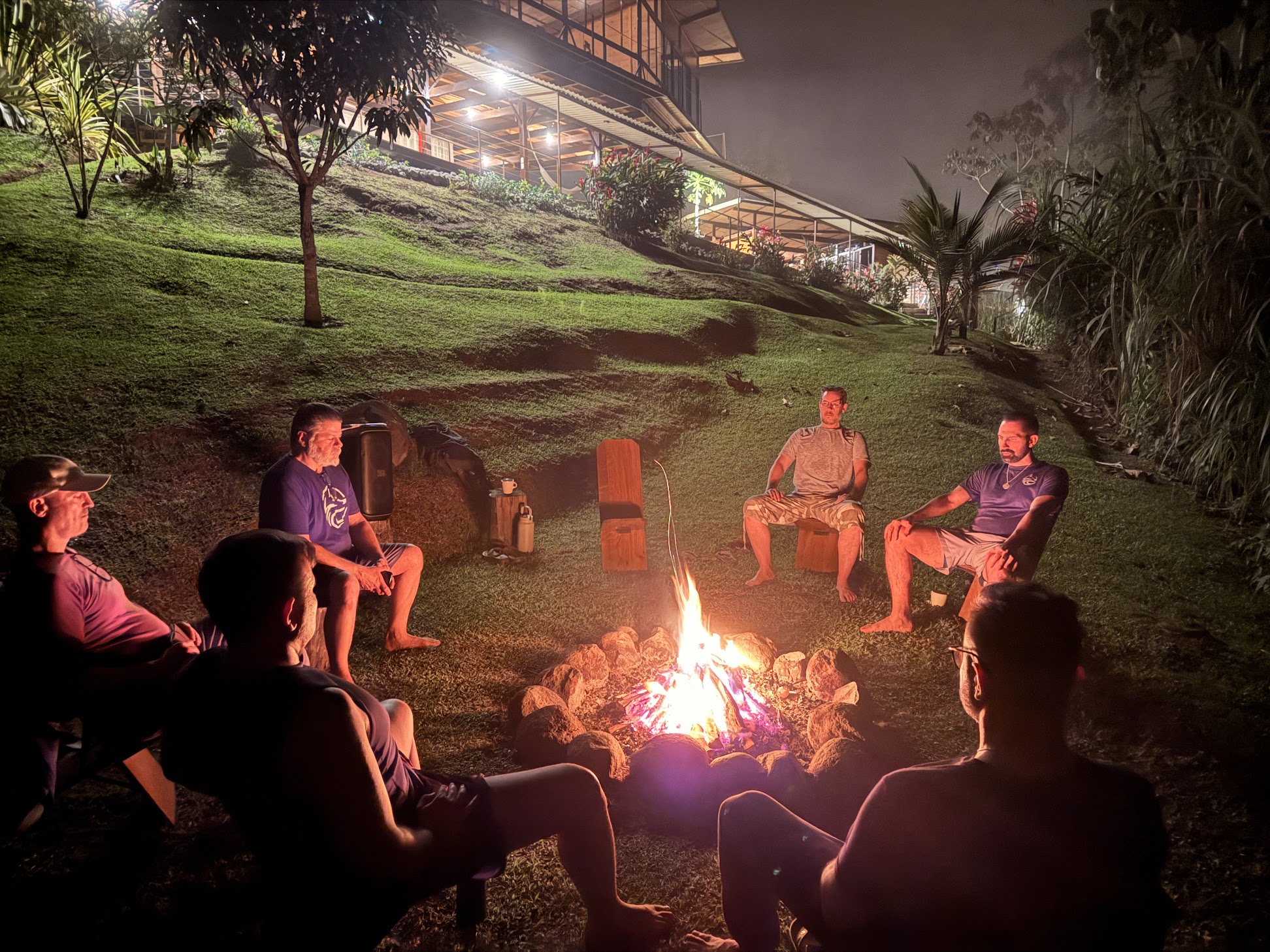 Brotherhood members gathered around a fire circle at night beneath the Costa Rica lodge, sharing honest conversation