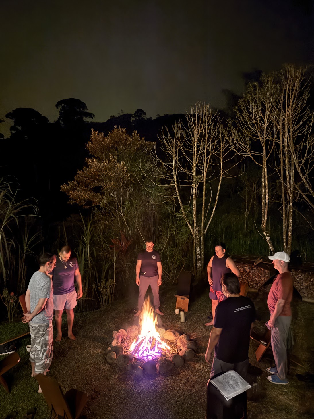 Brotherhood members standing around a fire during a nighttime ritual ceremony in the Costa Rica jungle